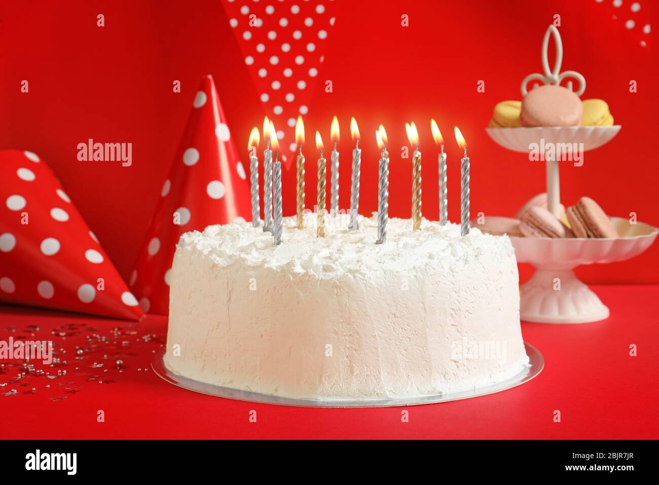 Birthday cake with candles on table against red wall Stock Photo - Alamy