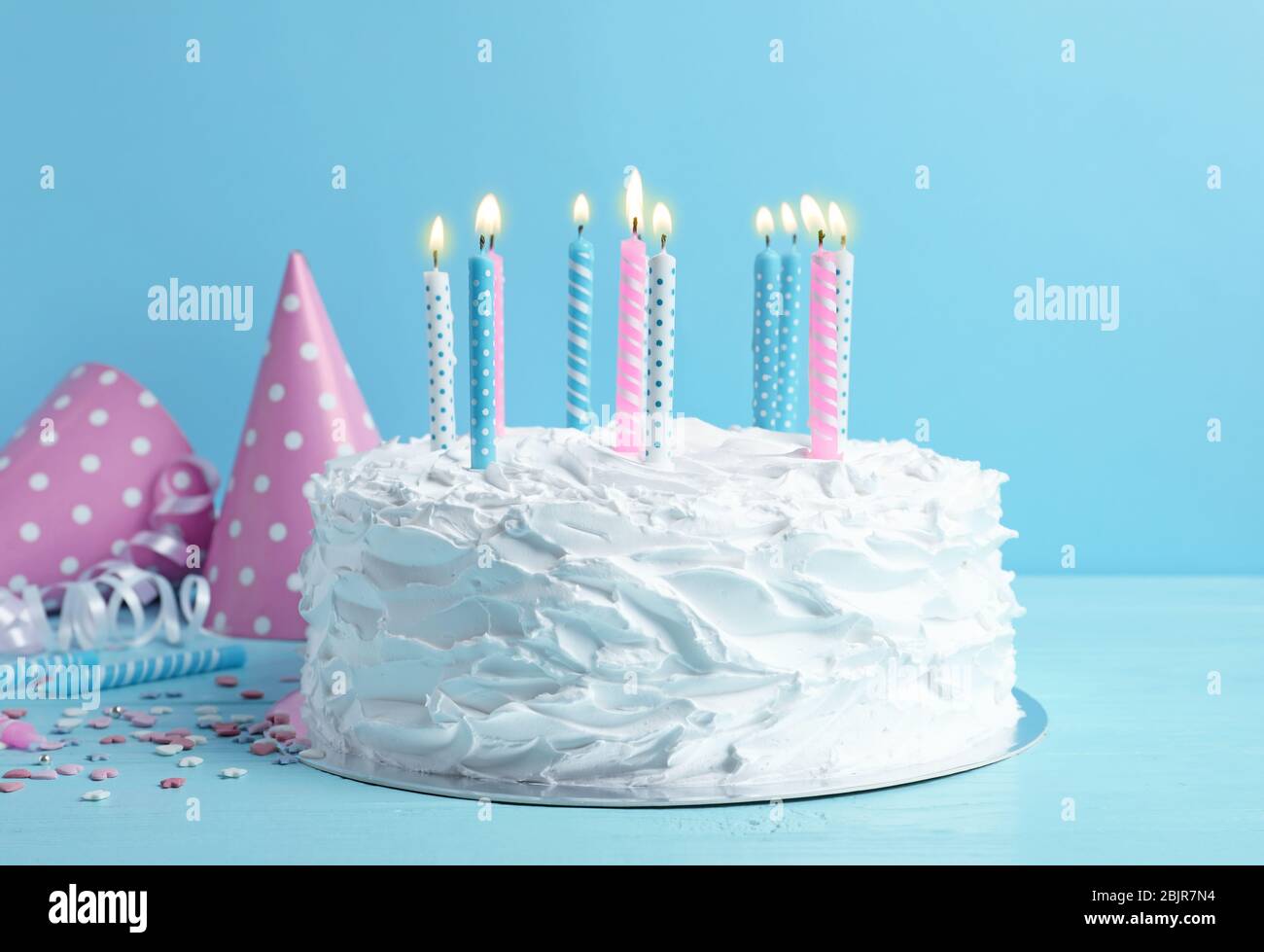 Birthday cake with candles on table against blue wall Stock Photo - Alamy