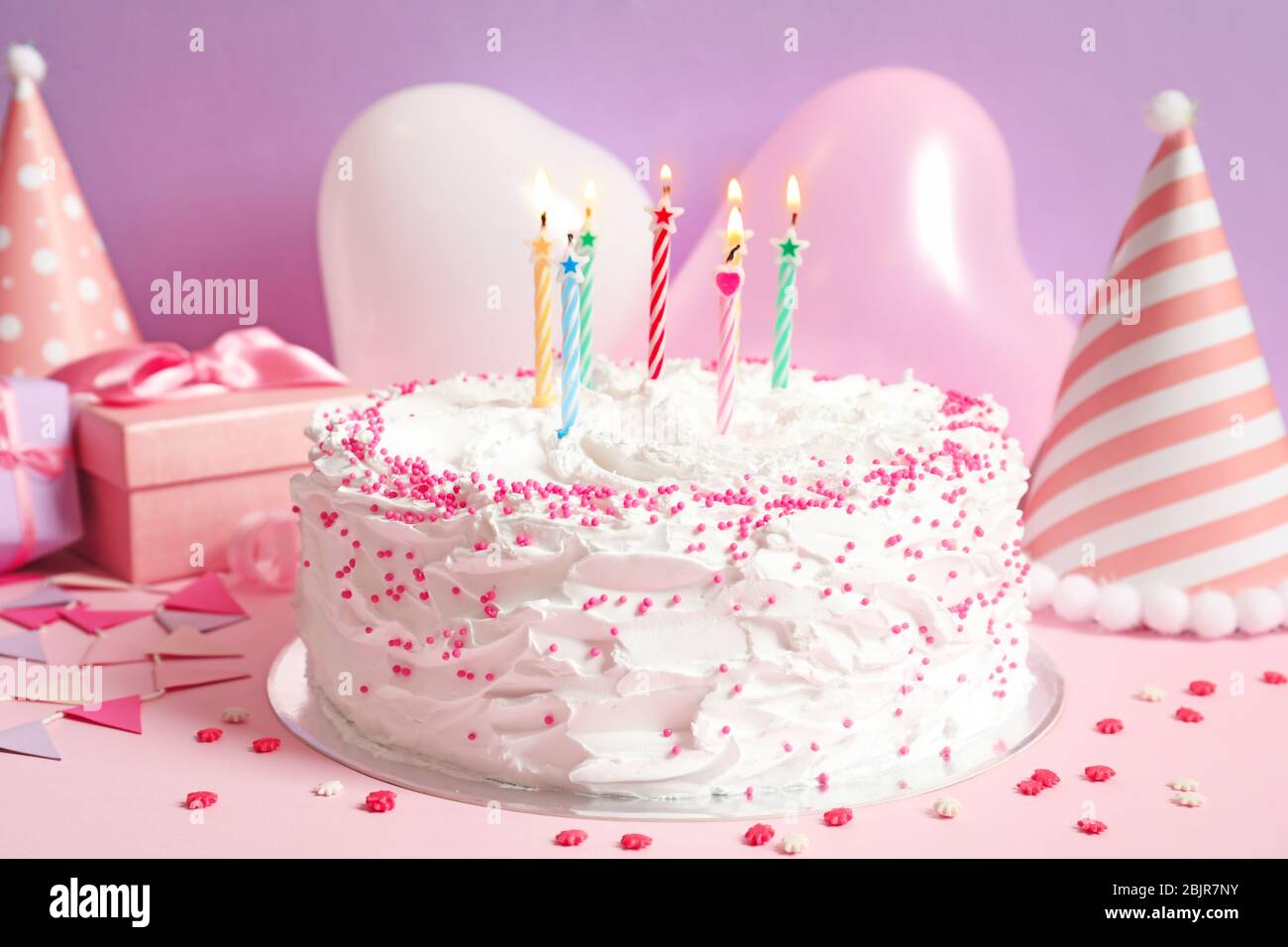 Birthday cake with candles on table against color wall Stock Photo - Alamy