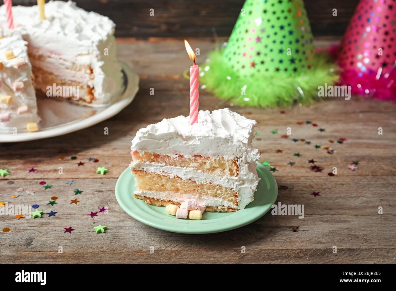 Piece of birthday cake with candle on table Stock Photo - Alamy