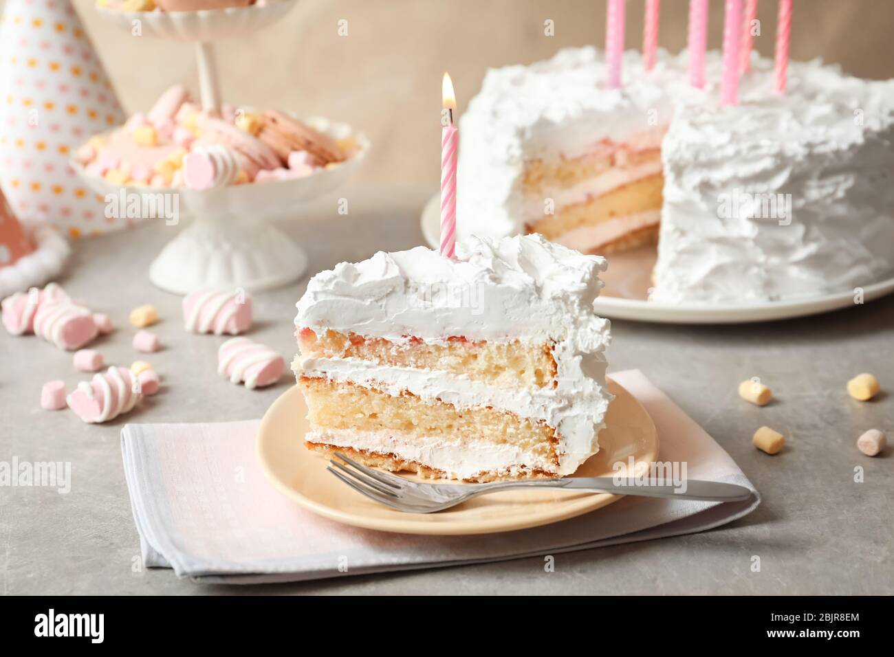Piece of birthday cake with candle on table Stock Photo - Alamy