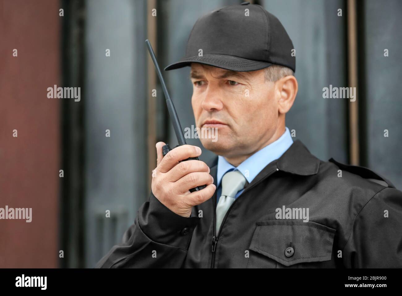 Male security guard using portable radio outdoors Stock Photo