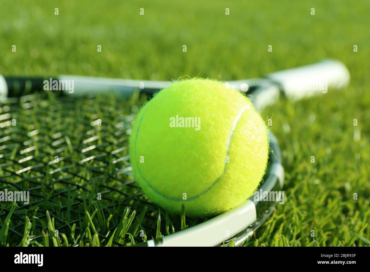 Tennis racket and ball on green grass Stock Photo - Alamy