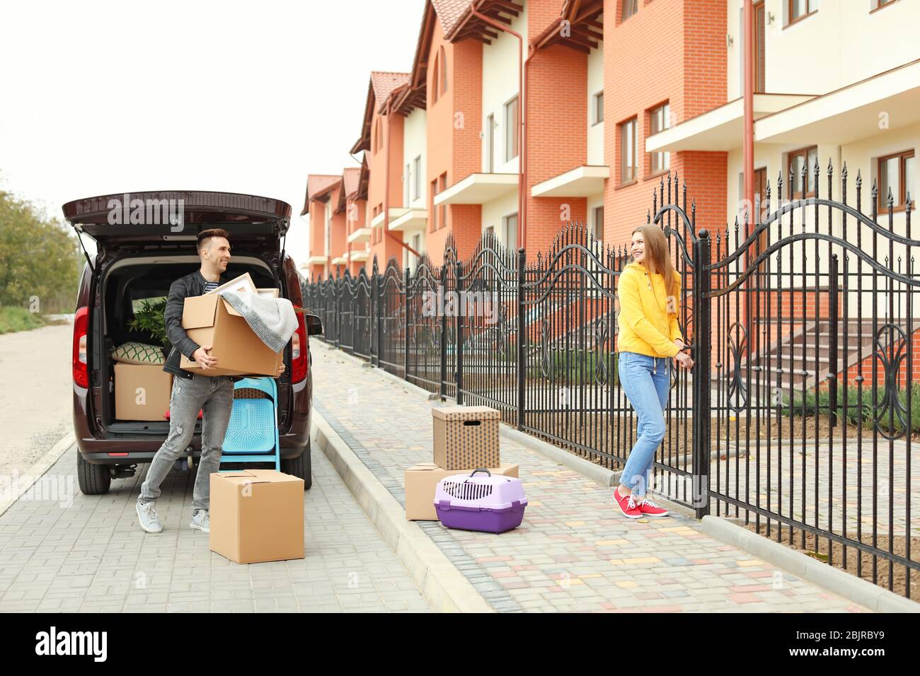 Young couple unloading boxes from their car on moving day Stock Photo