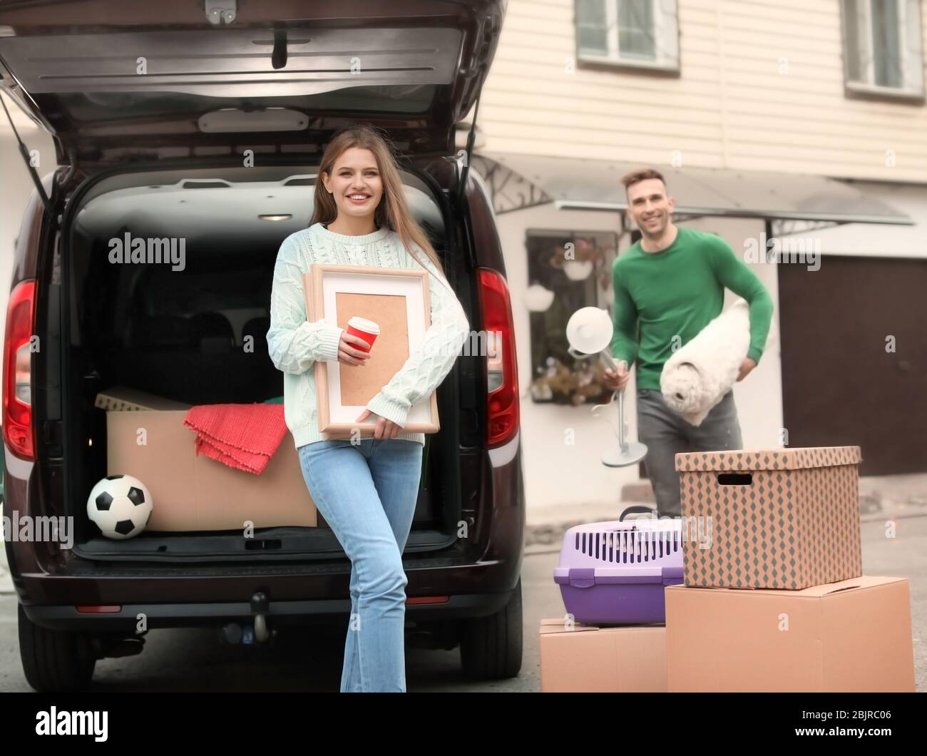 Young couple unloading boxes from their car on moving day Stock Photo