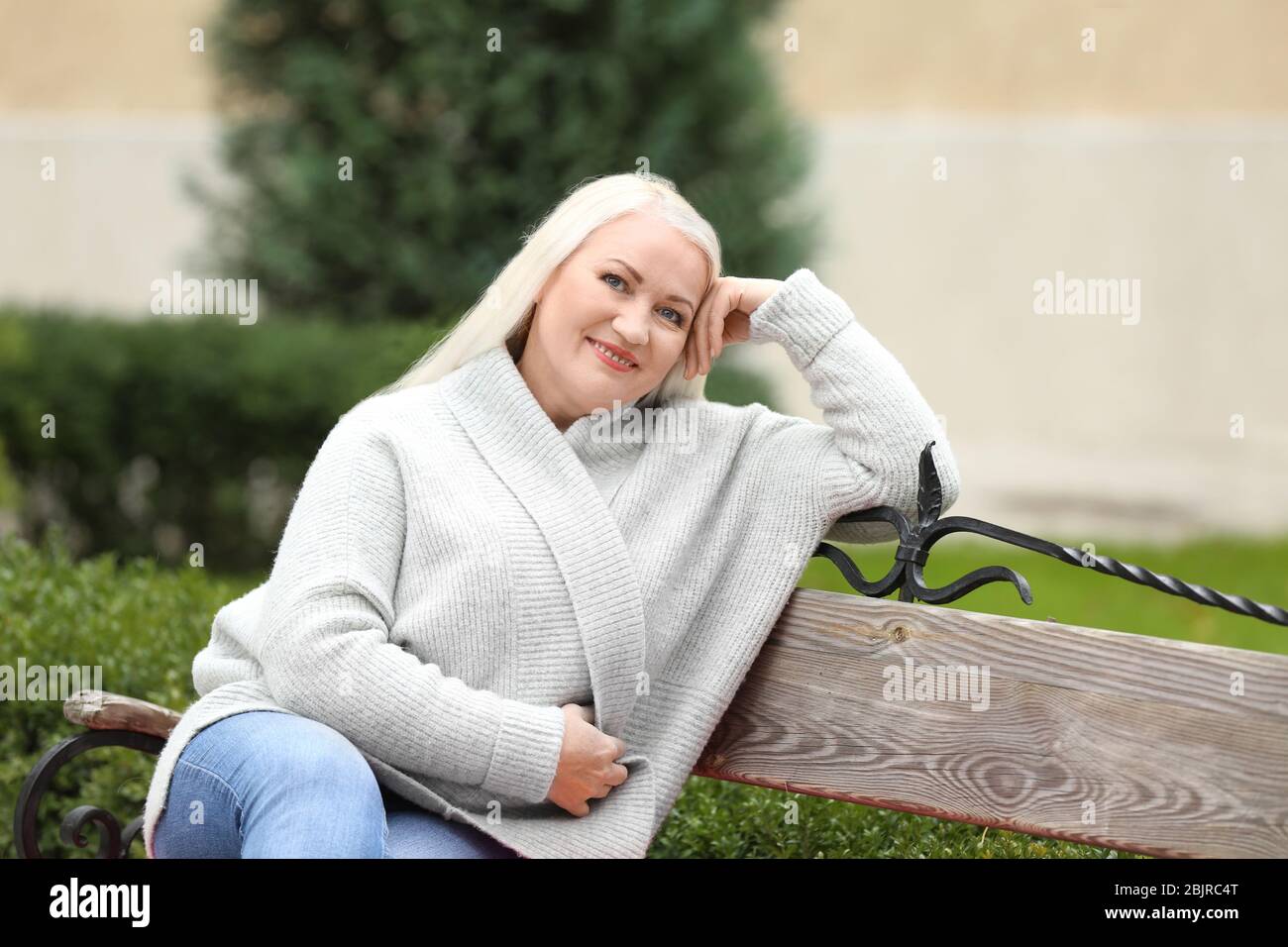 Beautiful mature woman sitting on bench in park Stock Photo - Alamy