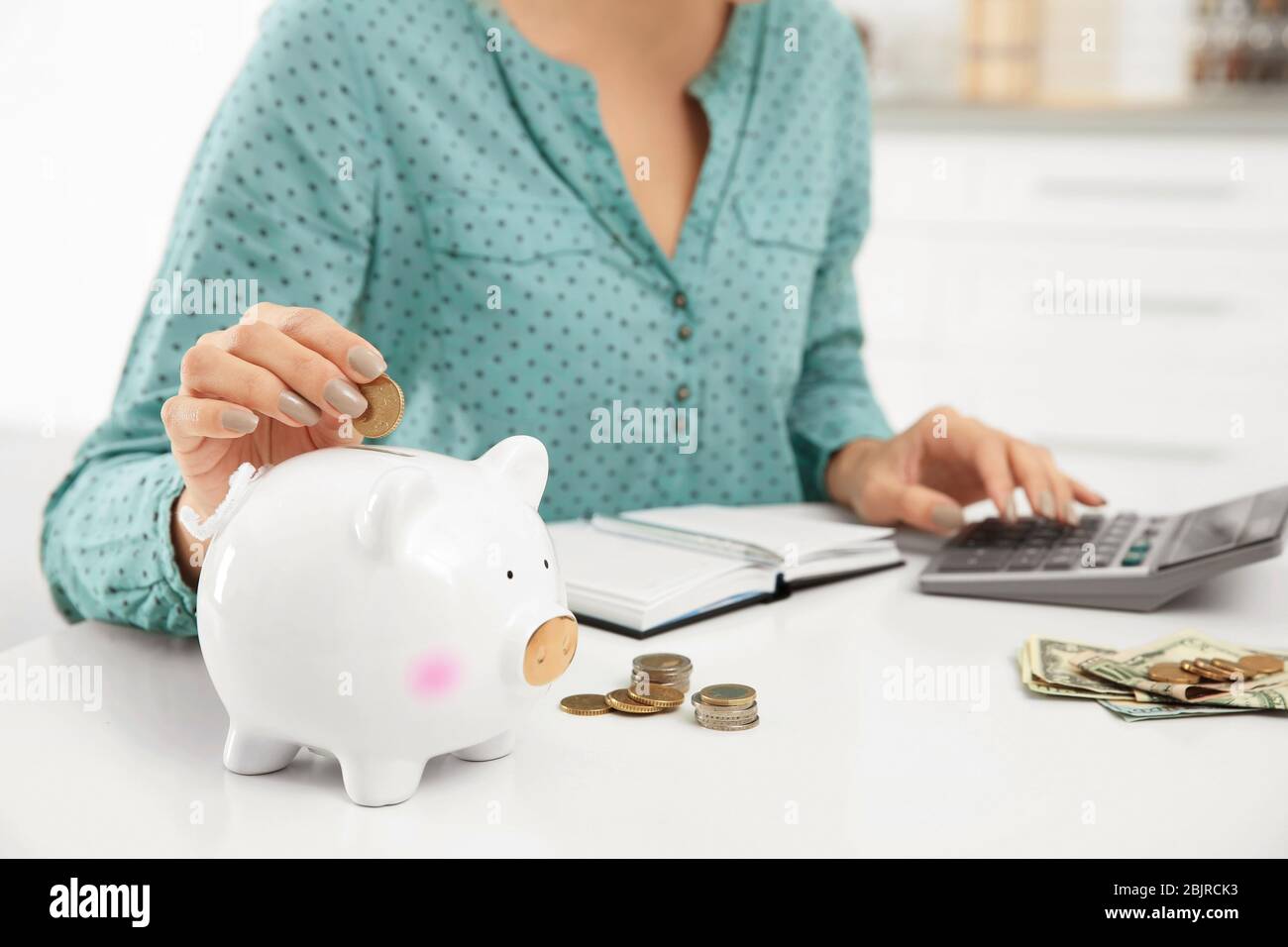 Woman putting coin into piggy bank, closeup Stock Photo - Alamy