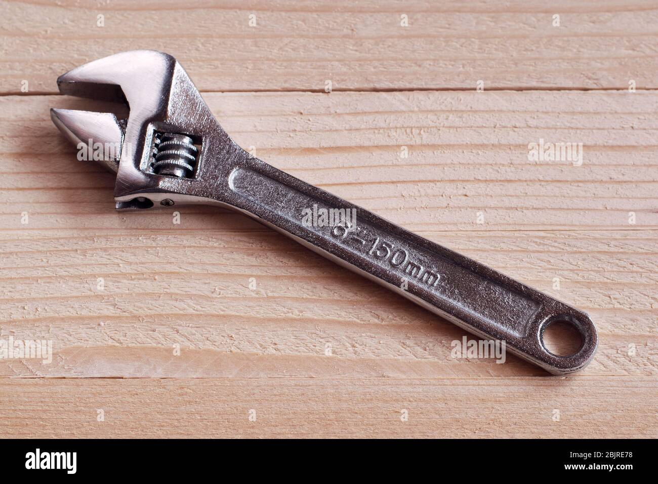 Chrome-plated adjustable wrench on a wooden background Stock Photo