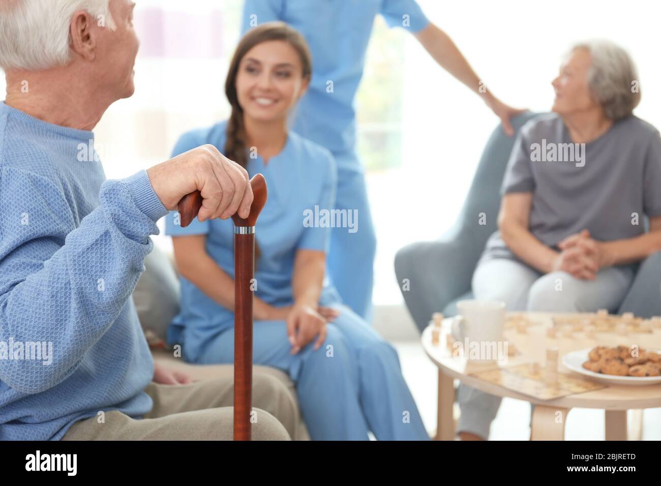 Senior man with cane and young caregiver indoors Stock Photo - Alamy