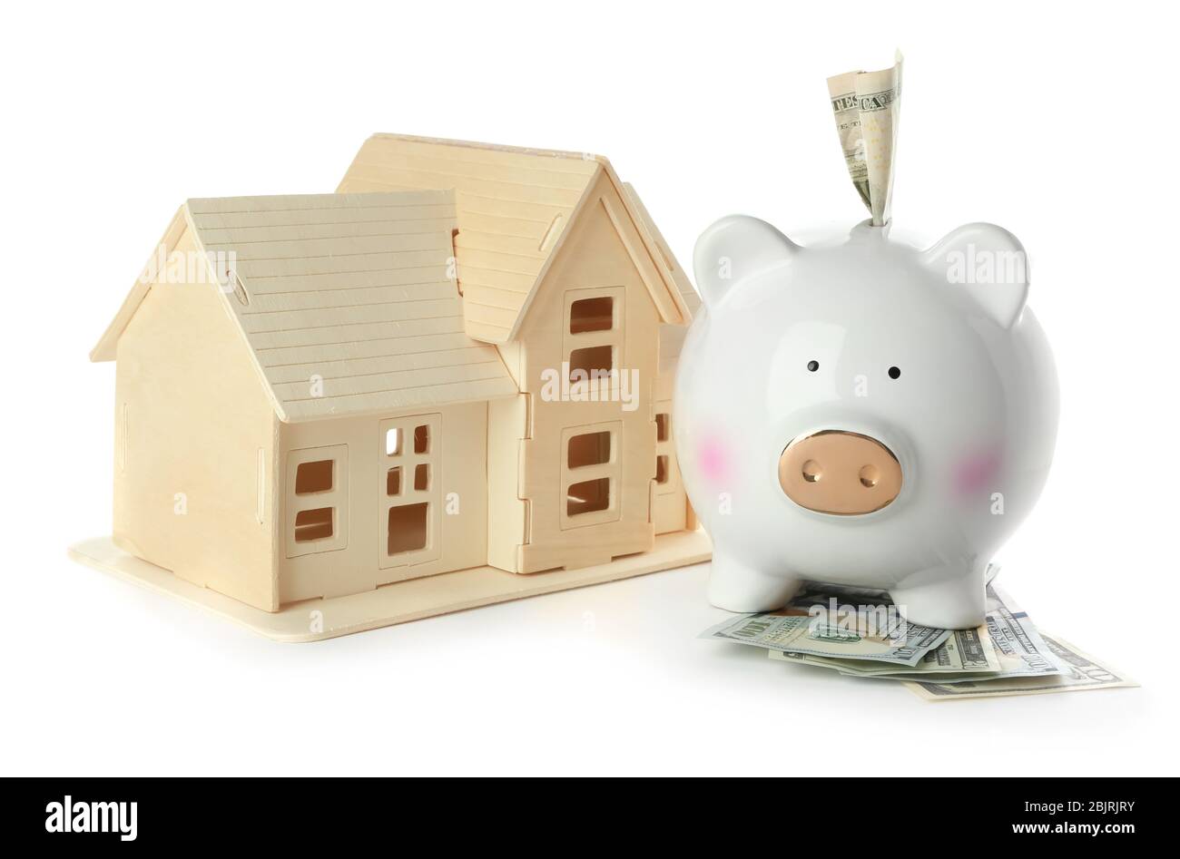 Ceramic piggy bank with money and model of house on white background ...