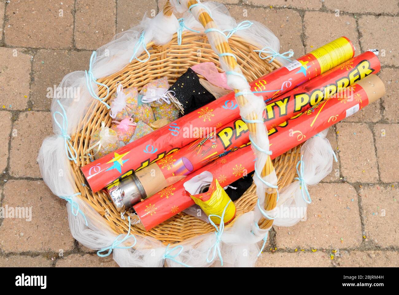 Bags of colored rice and tubes of party popper in a basket on the ground, ready to launch at a celebration Stock Photo