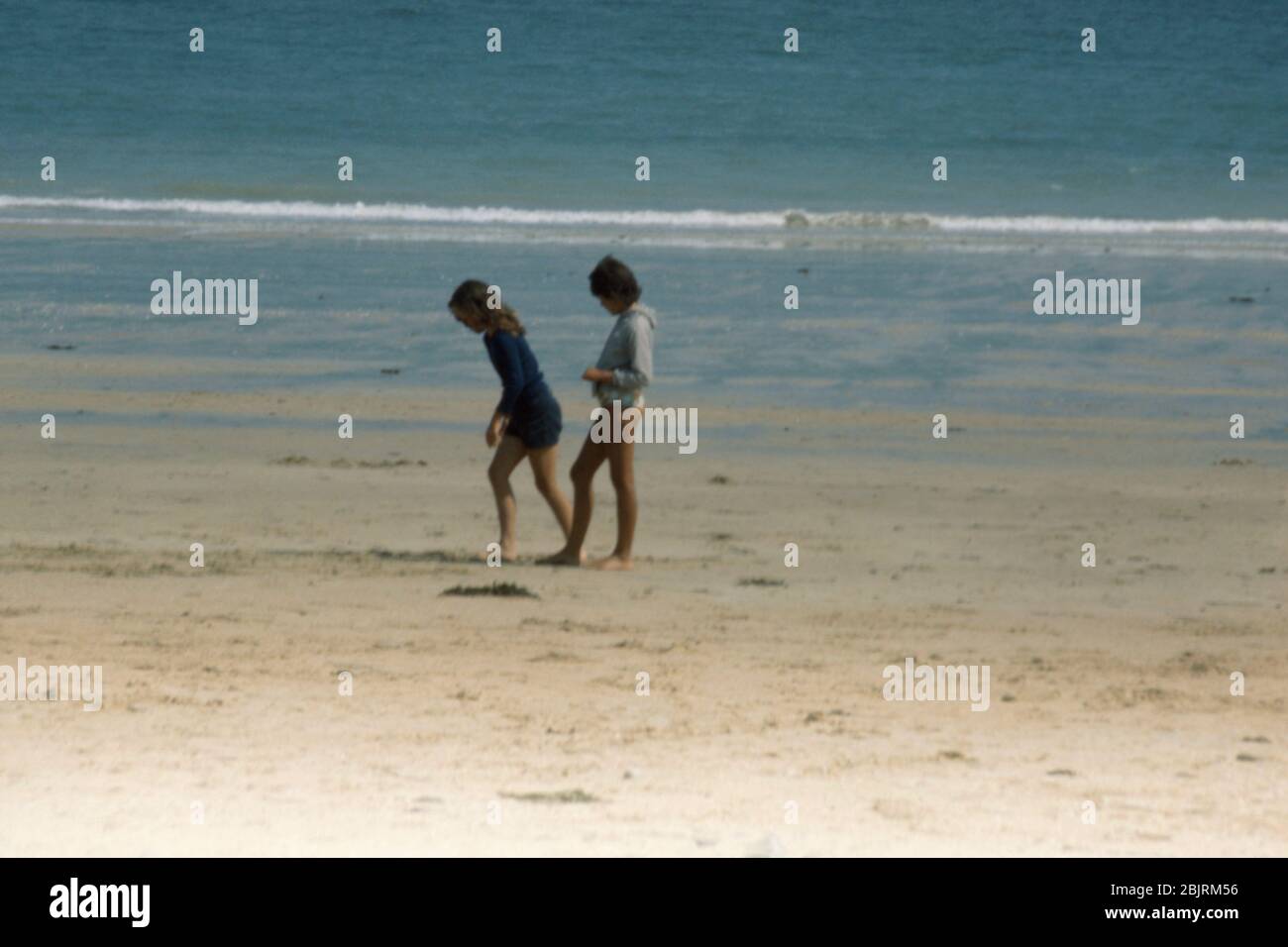 Two 9 years old girls beachcombing while the tide is out on the beach at St Cast Le Guildo, Brittany, France 1974. Stock Photo