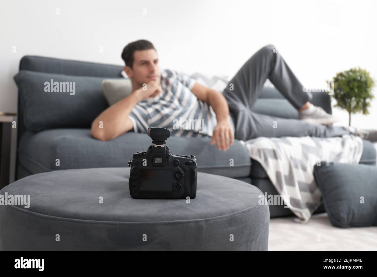 Young man posing on couch for professional camera indoors Stock Photo