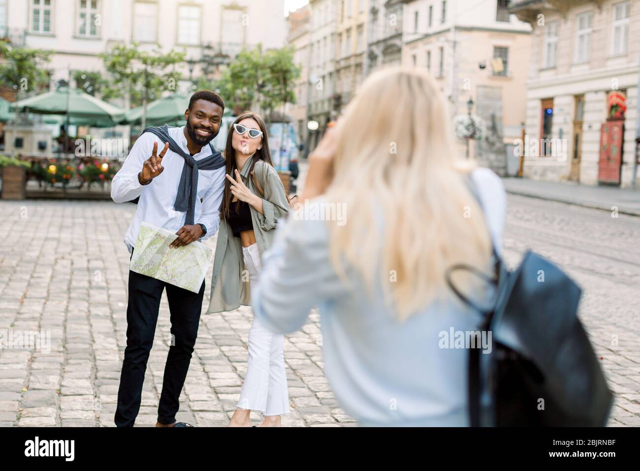 Excited cheerful mix raced couple, African man and Caucasian girl, enjoying walking outdoors, in the center of ancient European city, while their Stock Photo