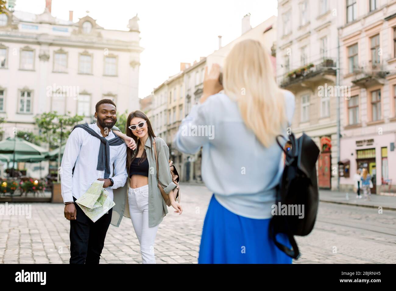 Excited cheerful mix raced couple, African man and Caucasian girl, enjoying walking outdoors, in the center of ancient European city, while their Stock Photo