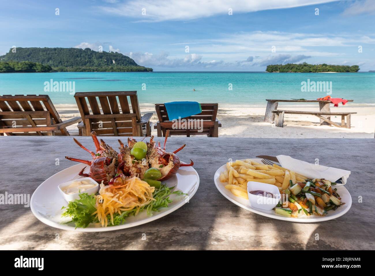 lobster with fries on white plate beach restaurant with beautiful view of paradise blue lagoon Stock Photo