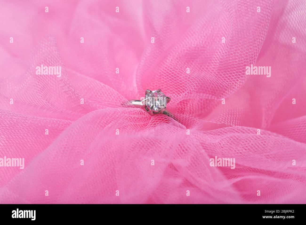 Beautiful engagement ring on pink tulle, closeup Stock Photo