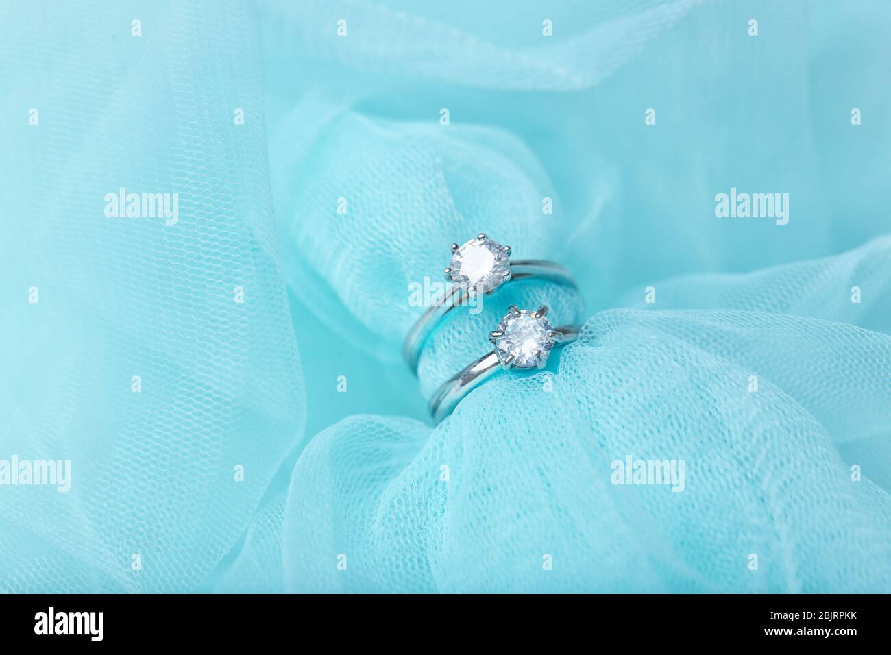 Beautiful engagement rings on color tulle, closeup Stock Photo