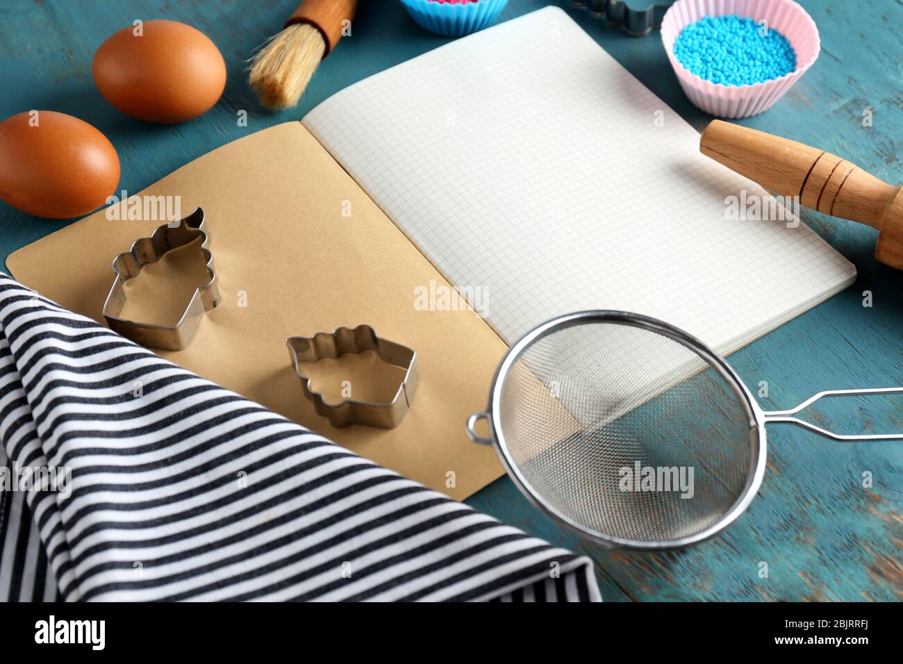 Blank notebook and kitchen utensils with ingredients for pastries on wooden table Stock Photo