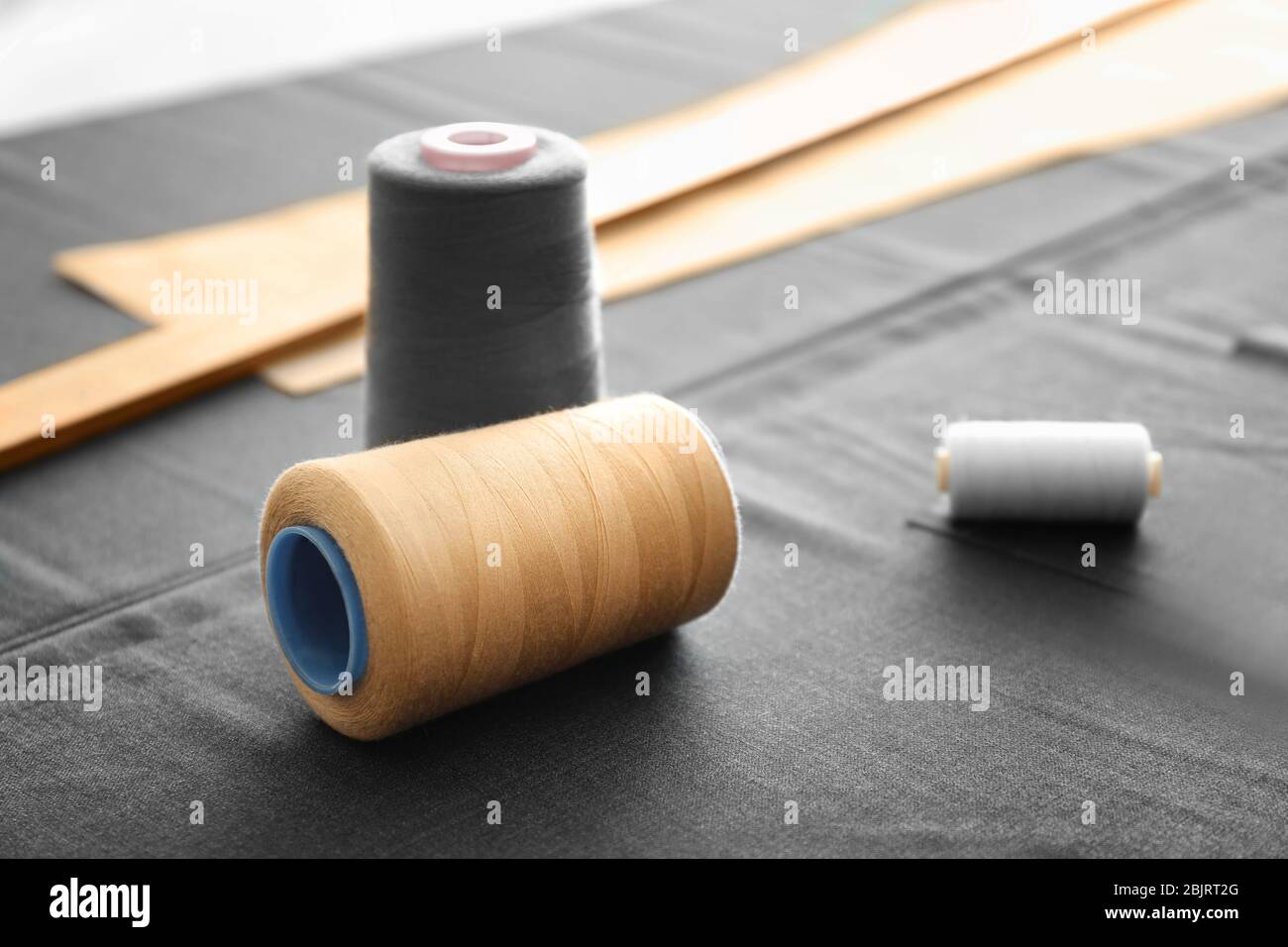 Sewing threads on grey fabric Stock Photo - Alamy
