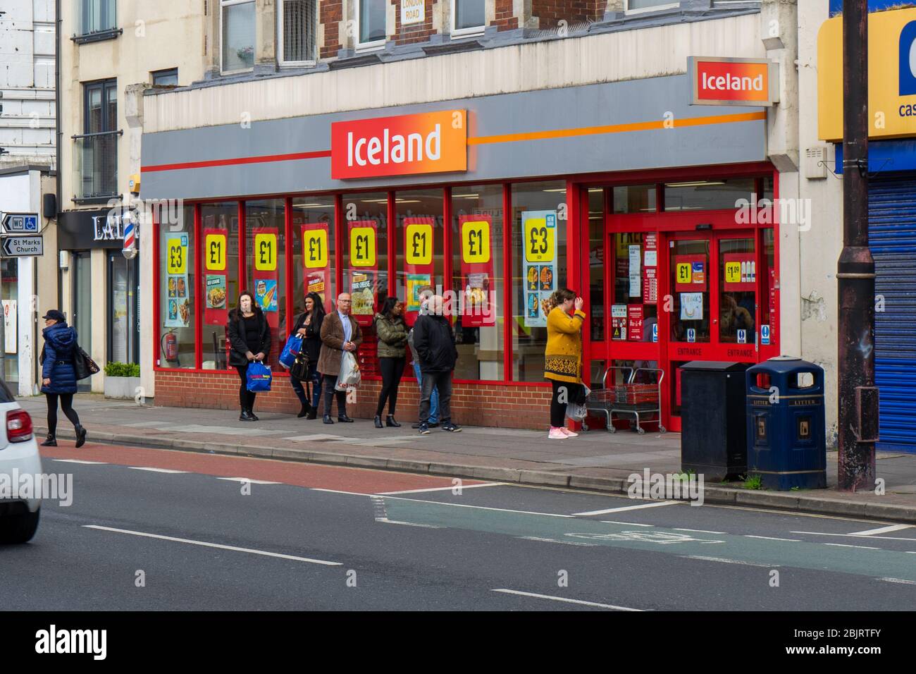 Shoppers performing social distancing while queuing outside an Iceland supermarket During the covid-19 pandemic Stock Photo