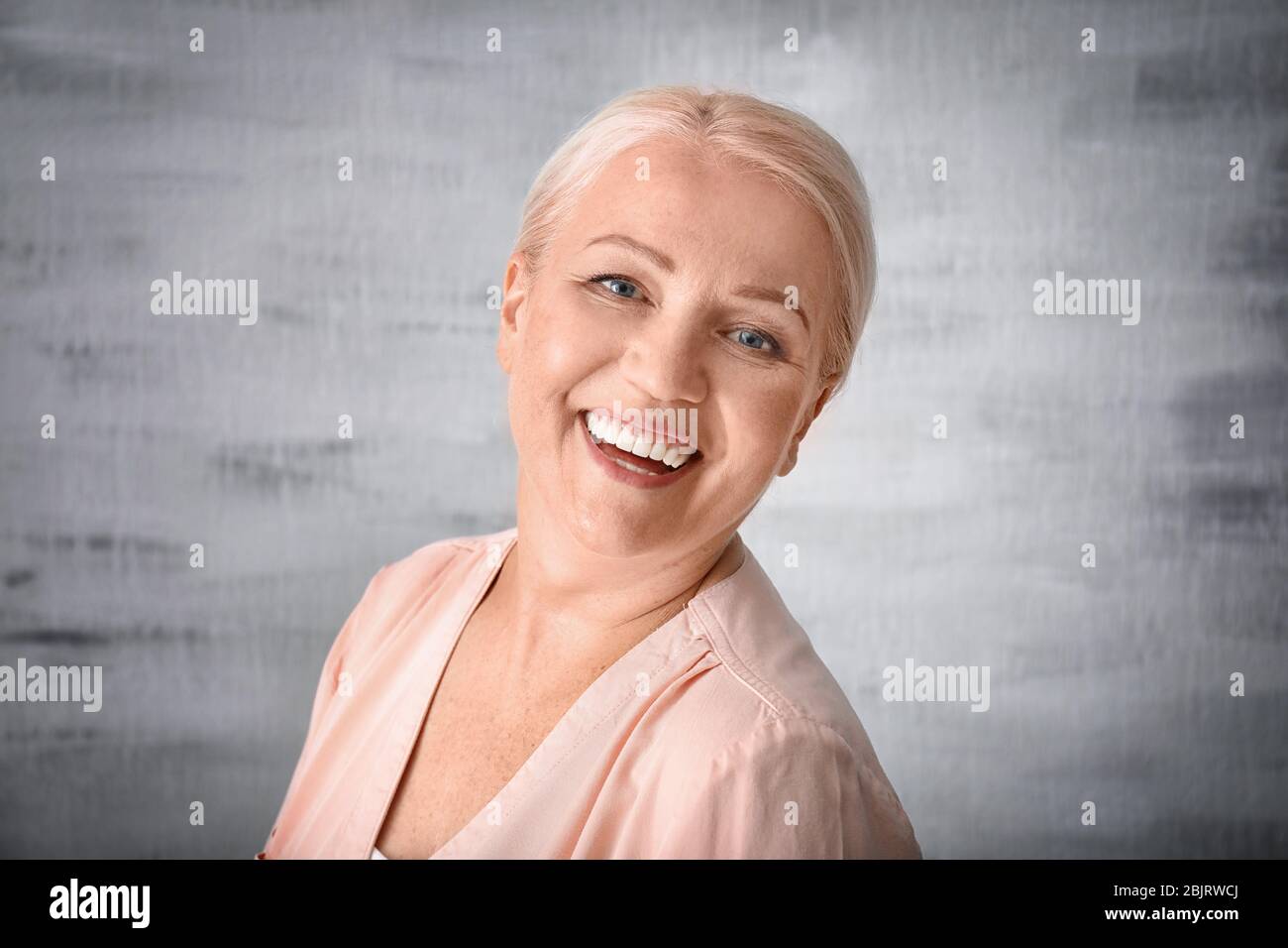 Portrait of smiling mature woman on grey background Stock Photo - Alamy