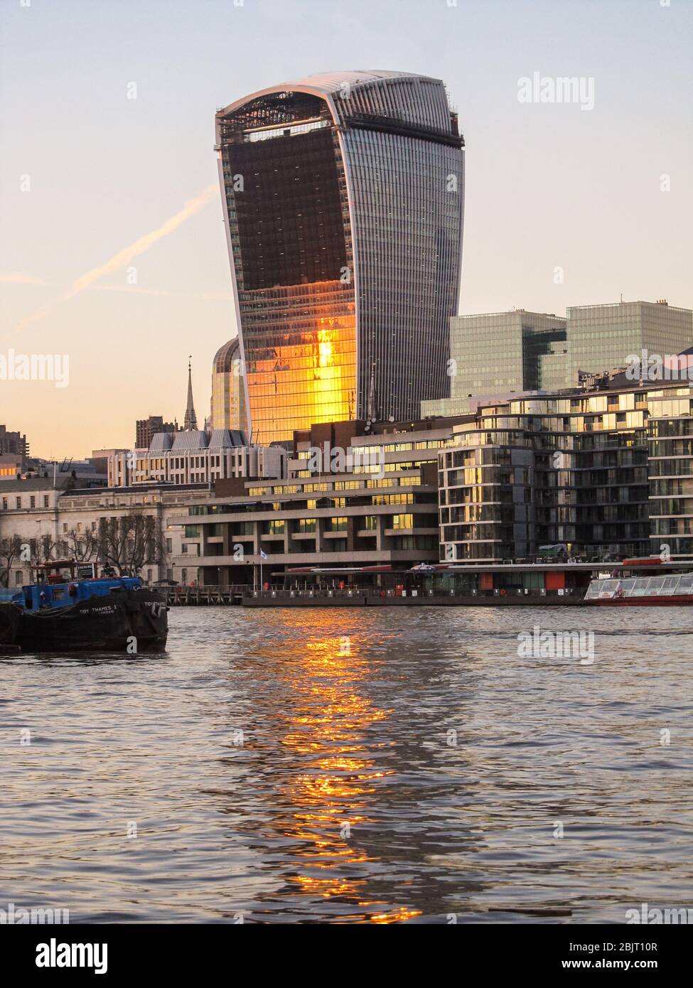 The Setting sun reflecting in the building of 20 Fenchurch Street, better known as the Walki Talki, which in turns reflects in the waters of the river Stock Photo