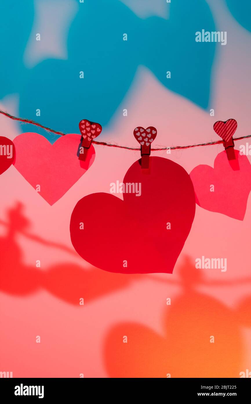 Paper hearts of red clothespins with a heart on a rope with a shadow ...