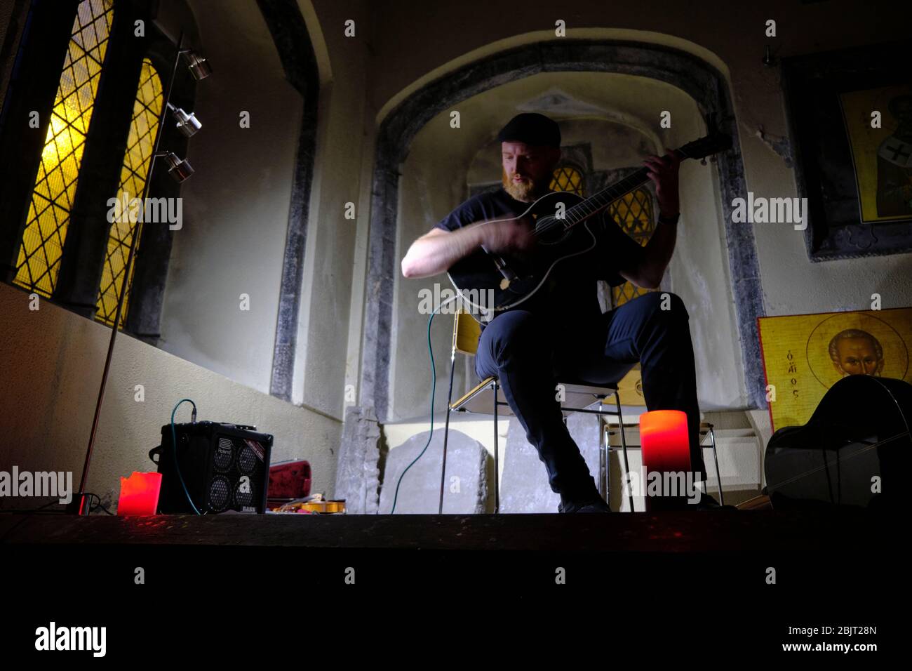 GALWAY, IRELAND - August 21 2019: a typical folk singer plays the guitar during a concert in an old church. Stock Photo