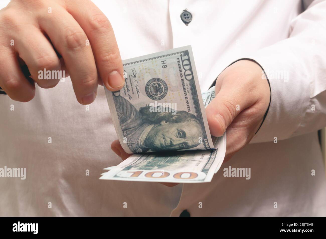 Caucasian man counts money hundred dollar bills in a white shirt in the office Stock Photo