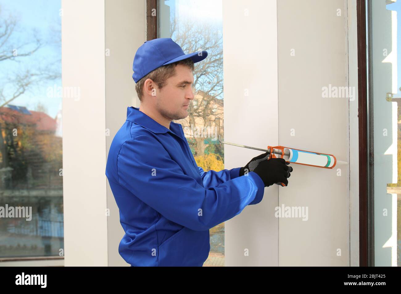 Construction worker repairing window in house Stock Photo - Alamy