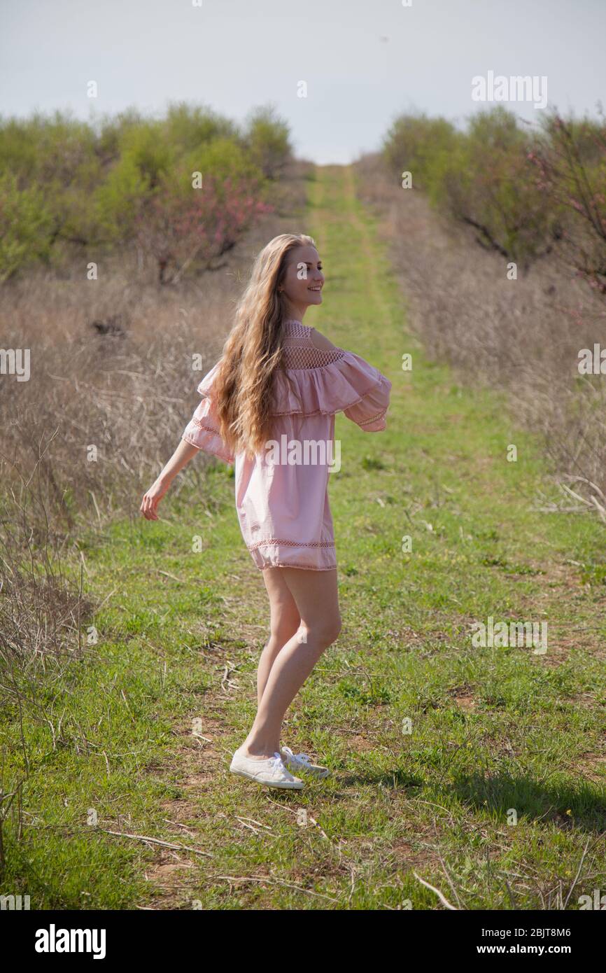 Woman blonde in pink dress runs the road Stock Photo