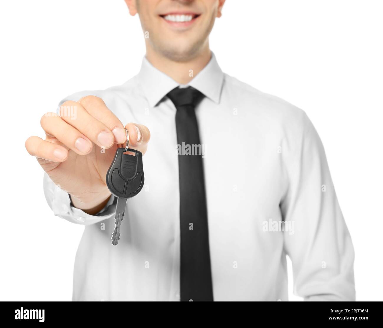 Young salesman holding car key on white background Stock Photo - Alamy