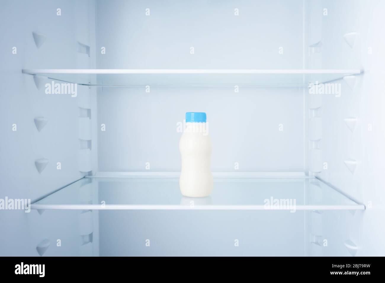 Bottle of milk in empty refrigerator Stock Photo