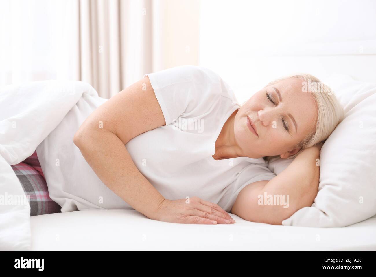 Senior woman sleeping on white pillow at home Stock Photo