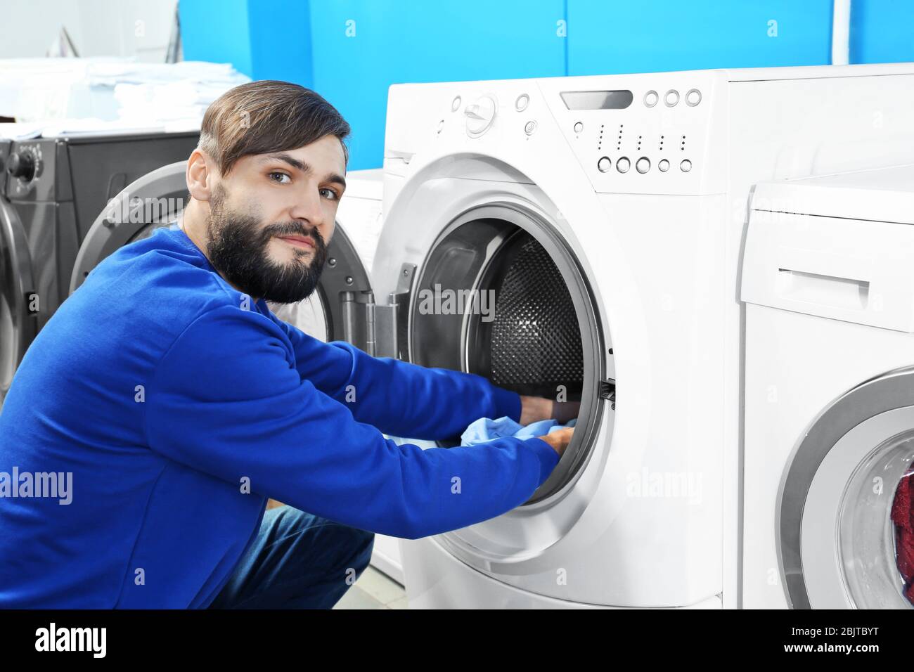 Man doing laundry in laundromat Stock Photo Alamy