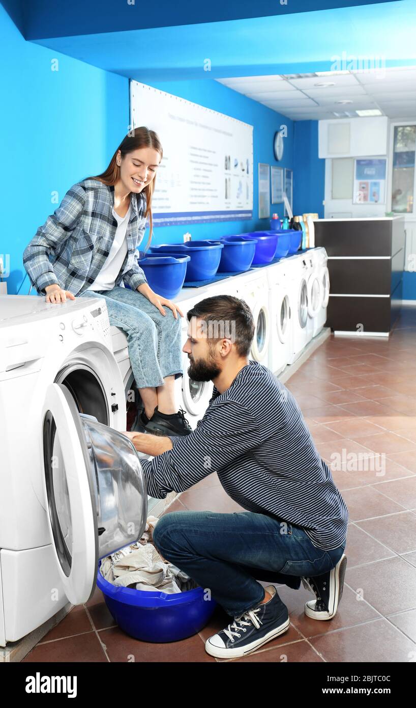 Young couple doing laundry in laundromat Stock Photo - Alamy