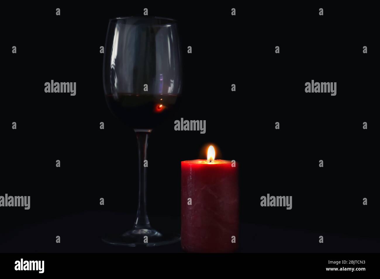 Burning candle and glass of wine on black background Stock Photo