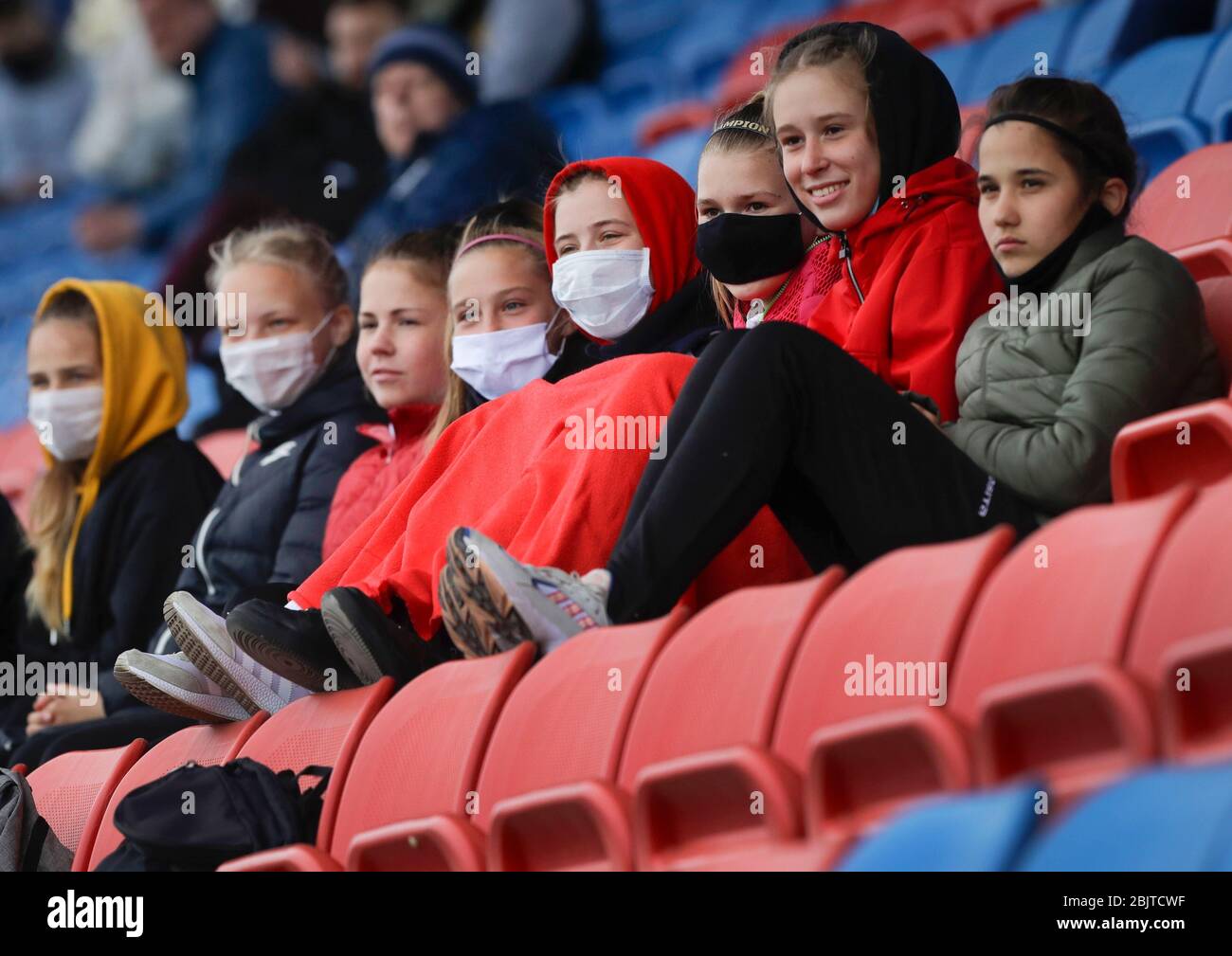 Fans wearing face masks to protect from coronavirus watch the Women's Major League soccer match between ABFF Women's Under-19 team and Dynamo-BGUFK in Minsk, Belarus, Thursday, April 30, 2020. Belarus is one of the few countries where professional soccer is still being played in front of spectators, and the only one in Europe. The World Health Organization is urging the government of Belarus to cancel public events and implement measures to ensure physical and social distancing amid the growing coronavirus outbreak. (AP Photo/Sergei Grits) Stock Photo