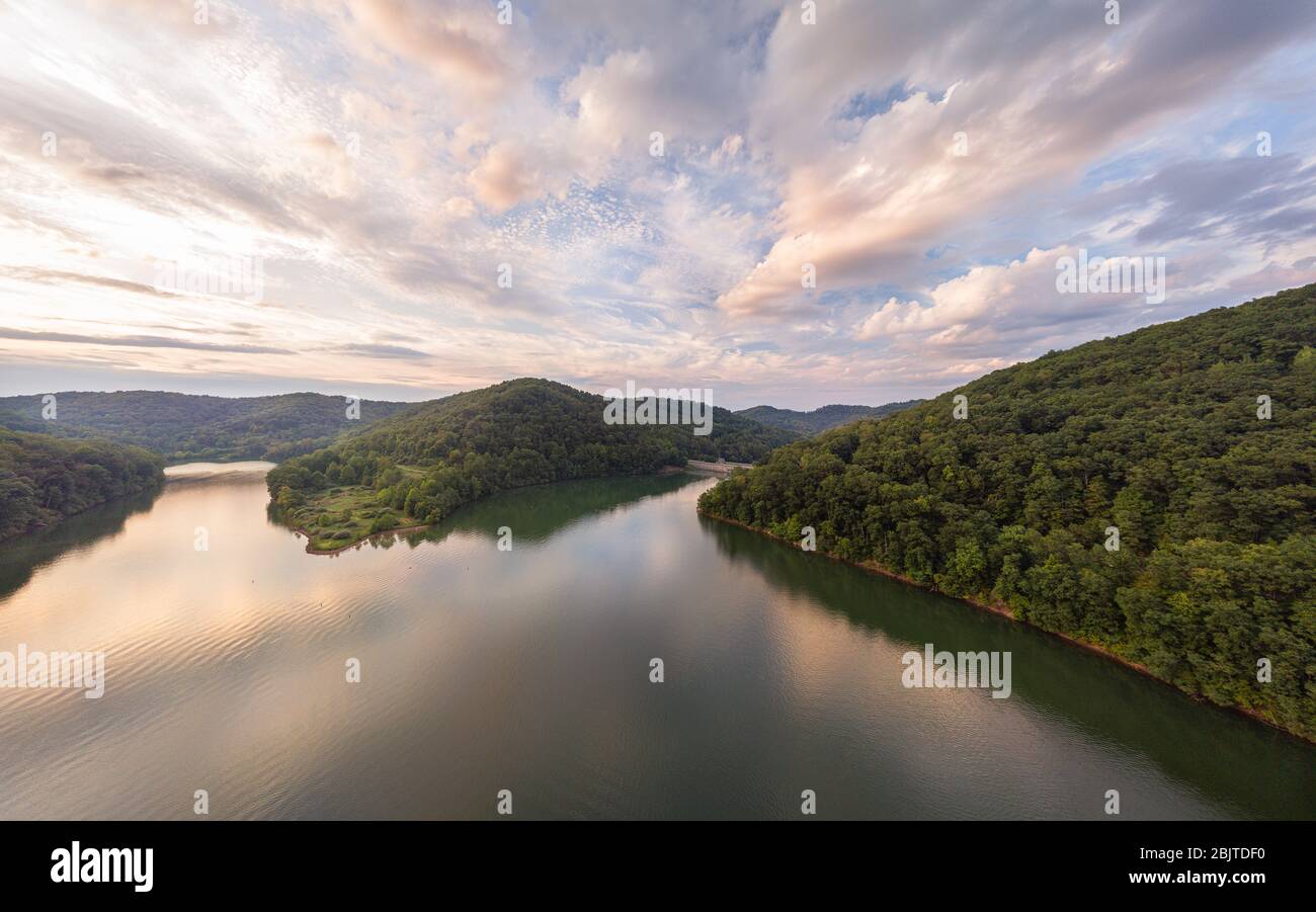 An aerial view of Stonewall Jackson Lake and the dam in the distant foreground with clouds overhead at sunset. Stock Photo