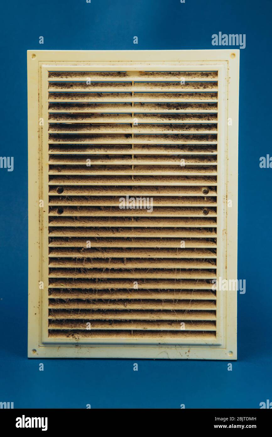 Extremely dirty and dusty white plastic ventilation grill for the home on a blue background. Hygiene. Stock Photo