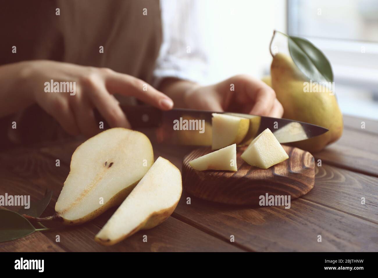 Young woman cutting fresh ripe pear on wooden board Stock Photo - Alamy