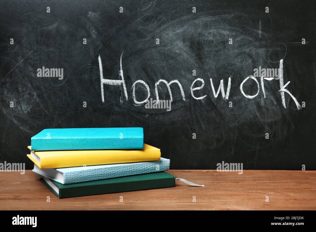 Notebook With Homework Notebooks on table near chalkboard with word