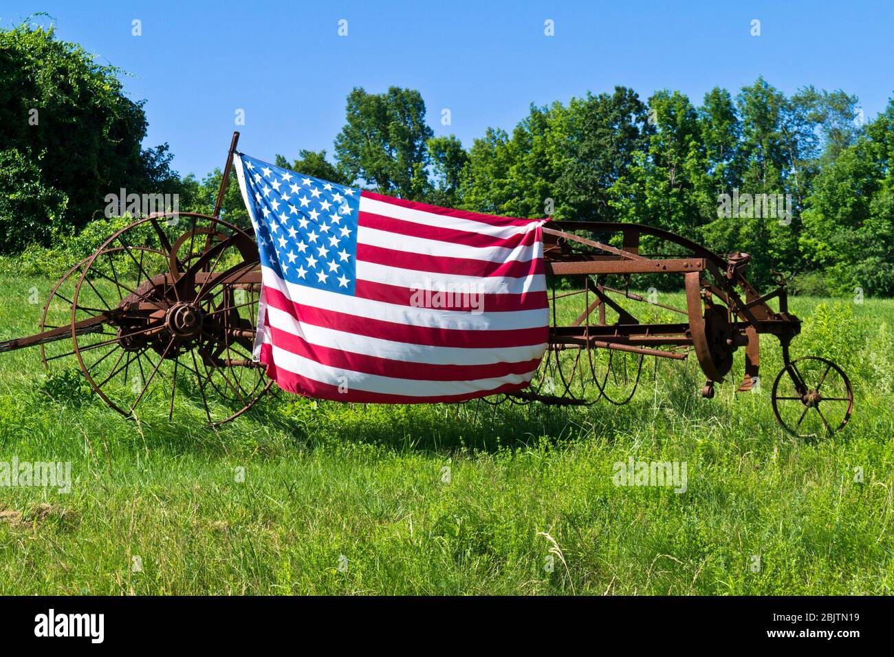 An American flag attached to farm equipment in a field in Barre, Massachusetts Stock Photo