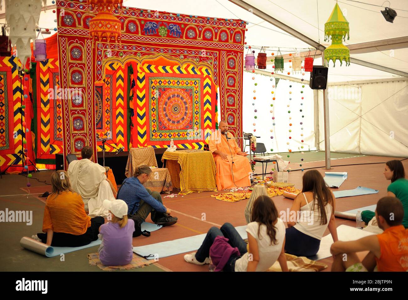 People sitting on the floor and listening to guru preaching during