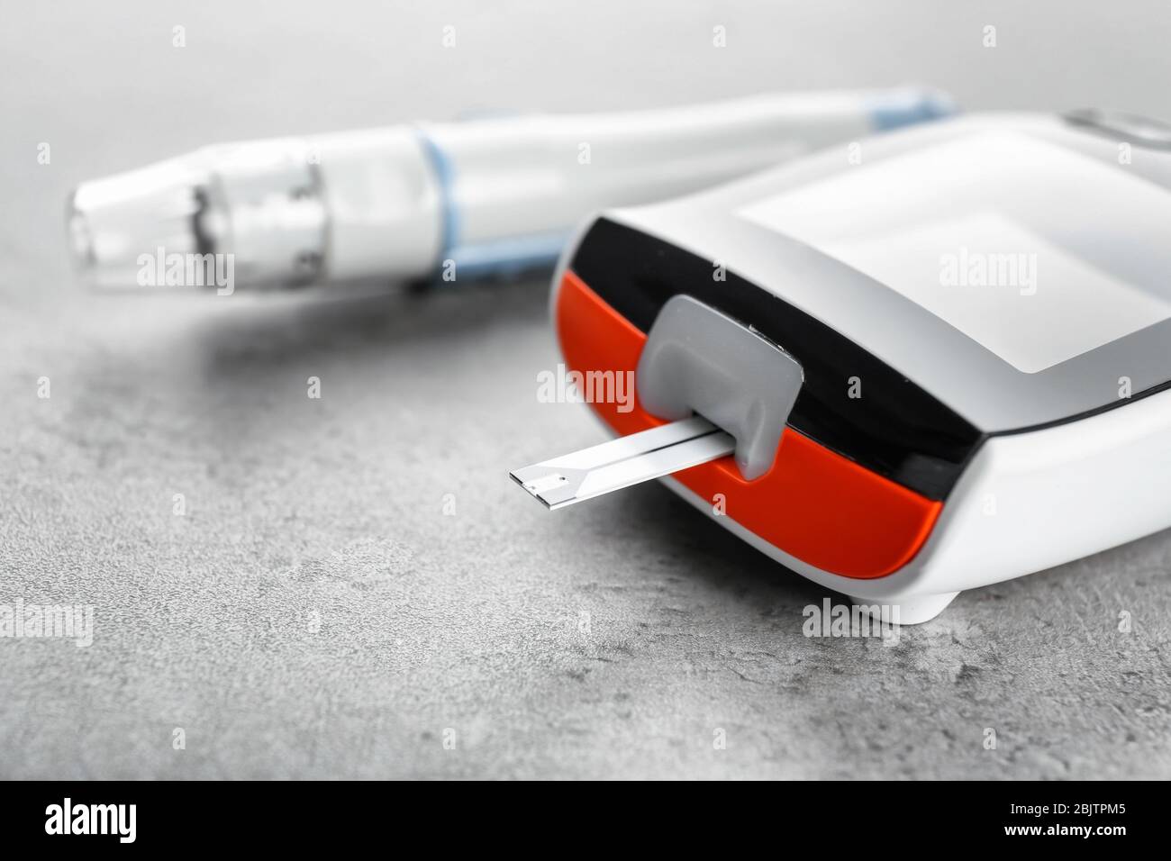 Digital glucometer on grey background. Diabetes management Stock Photo