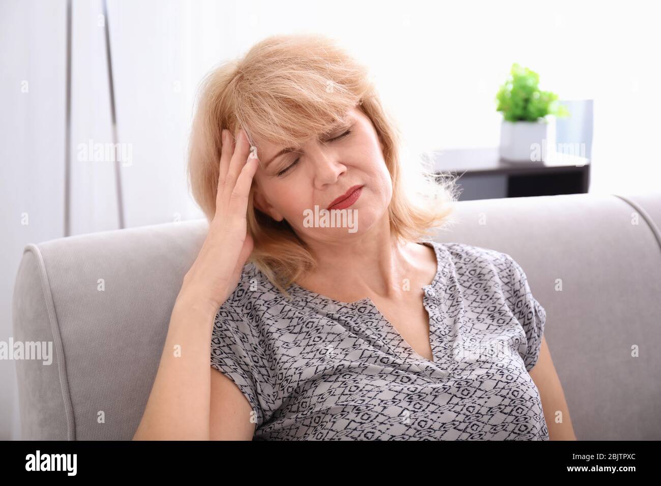 Mature woman suffering from headache at home Stock Photo