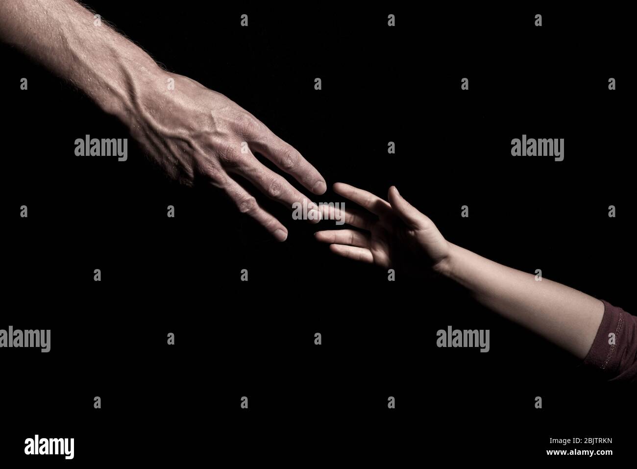 Hands reaching out to each other on dark black background Stock Photo ...