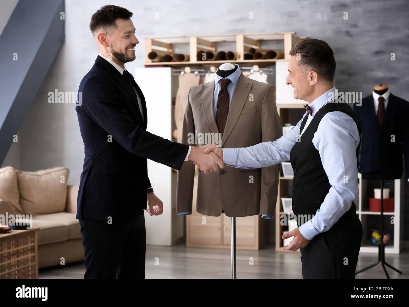 Tailor shaking hands with client in atelier Stock Photo - Alamy