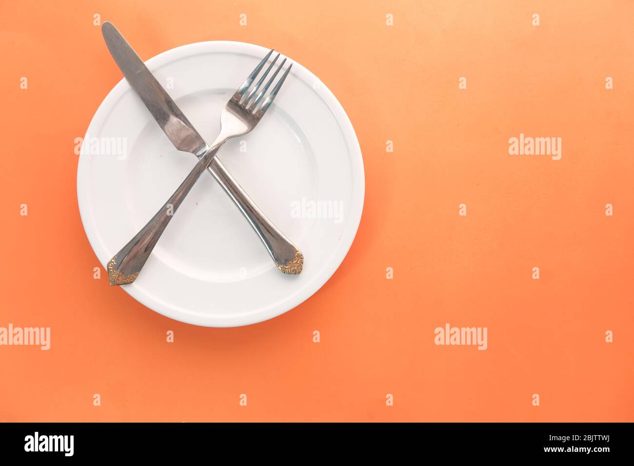 empty plate with fork and knife on orange . Stock Photo